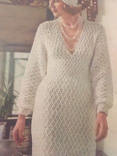 an old photo of a woman in a white dress and hat with pearls on her head