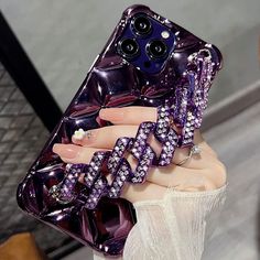 a woman holding up a purple phone case with jewels on it's sides and her hand in the air