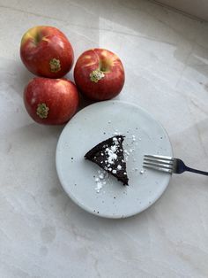 a piece of cake on a plate next to apples