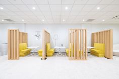 an office with white walls and yellow chairs in the center, along with wooden partitions for privacy