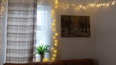 a living room with lights strung from the ceiling and a couch in front of a window