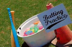 a bucket full of gummy bears sitting next to a bat and baseball glove on the grass