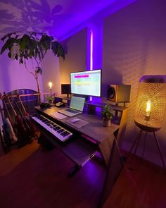 a computer desk with a laptop and keyboard on it in front of a purple light