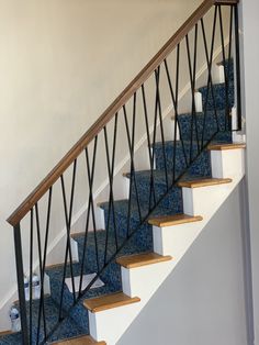 there is a blue carpeted stair case next to the white wall and flooring