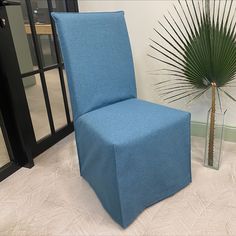 a blue chair sitting next to a tall plant in a room with white carpeting