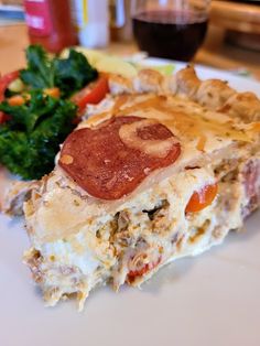 a piece of pizza sitting on top of a white plate next to a green leafy salad