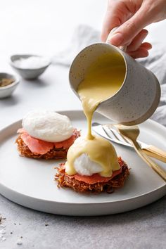 someone pouring sauce on some food on a plate