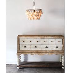 an old dresser with two drawers and a light fixture hanging from the ceiling above it