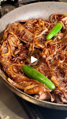 a skillet with onions and green peppers cooking on the stove