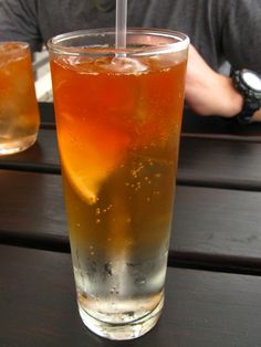 a glass filled with liquid sitting on top of a wooden table