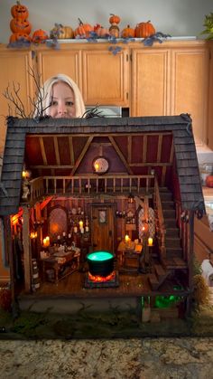 a woman is looking at a doll house made out of wood and fake pumpkins