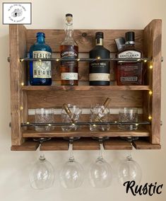 a wooden shelf with wine glasses and liquor bottles on it, hanging from the wall