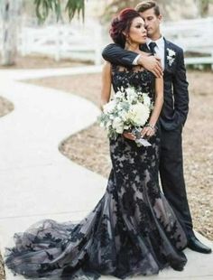 a man and woman standing next to each other in front of a walkway with trees