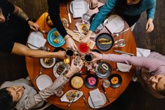 a group of people sitting at a table with food and drinks in their hands, top view