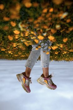 a person jumping up into the air with their shoes on and orange trees in the background