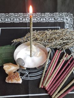 a candle is sitting in a bowl with some incense sticks and other items around it