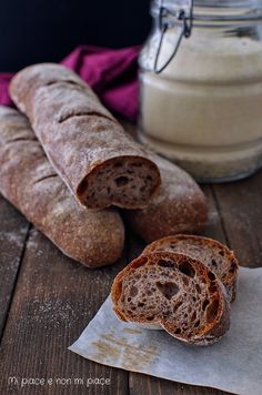 two loaves of bread sitting on top of a piece of paper next to a jar