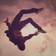 a man flying through the air while riding a skateboard in front of a cloudy sky