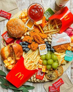 a cheeseburger, french fries, grapes and other snacks are arranged on a plate