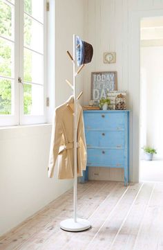 a coat rack with hat and jacket hanging on it in front of a blue dresser