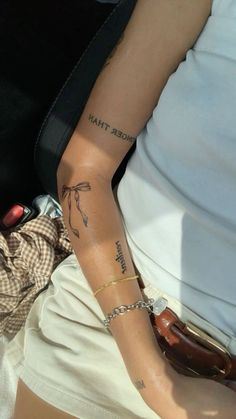 a woman sitting in the back seat of a car holding onto her arm with tattoos on it