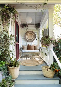 the front porch is decorated with plants and wicker furniture, including an outdoor sofa