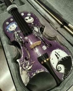 a purple violin sitting on top of a metal counter next to a pair of scissors