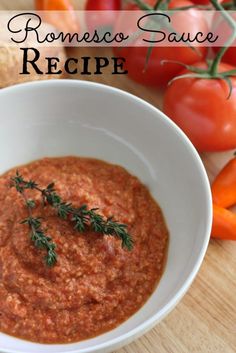 a white bowl filled with tomato sauce next to tomatoes