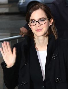 a woman wearing glasses waves to the crowd