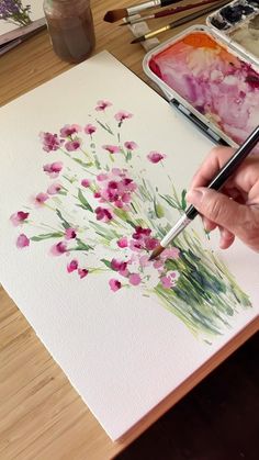 a person is painting flowers with watercolors