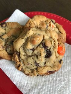 two chocolate chip cookies sitting on top of a red plate next to a white napkin