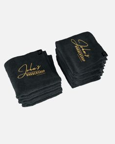 six black towels with gold lettering on the front and one is folded up to show it's logo