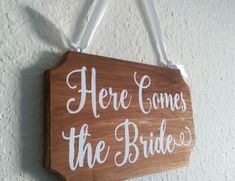 there is a wooden sign that says here comes the bride on it hanging from a wall