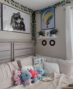 there are stuffed animals on the bed in this room with two pictures above it and below them