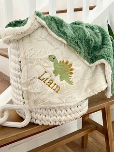 a green and white blanket sitting on top of a wooden bench next to a chair