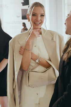 a woman wearing a white jacket and holding her hand on her chest, standing next to two other women