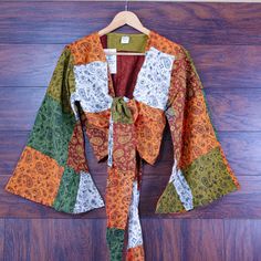 Add a dash of bohemian charm to your wardrobe with this colorful paisley print bell sleeve patchwork top. Perfect for festival lovers and free-spirited souls alike. Design & Print: Paisley Print: Features a whimsical mix of paisley prints in earthy tones. Colorful Patchwork: Crafted from a vibrant combination of warm colors including oranges, greens, and browns. Bell Sleeves & Crop Length: Bell Sleeves: Wide, flowing sleeves add a dramatic and stylish flair. Crop Length: Finished with a flattering tie-front closure at the waist. Material & Fit: Material: Made from lightweight and breathable cotton for comfort. Fit: Relaxed fit makes it ideal for layering over a tank top or bikini. Boho Style: Perfect for music festivals, beach outings, or casual everyday wear. Embodies the free-spirited hi Green Bohemian Tops For Fall, Green Boho Print Long Sleeve Top, Green Long Sleeve Top With Boho Print, Green Long Sleeve Boho Print Top, Multicolor Boho Print Long Sleeve Tops, Multicolor Bohemian Long Sleeve Blouse, Multicolor Long Sleeve Bohemian Blouse, Bohemian Multicolor Long Sleeve Blouse, Bohemian Multicolor Blouse For Fall