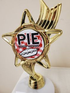 a gold trophy with a pie logo on it's face and the words pie eating contest