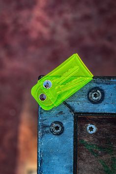 a green plastic object sitting on top of a blue wooden structure with rivets