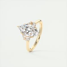 a yellow gold ring with a pear shaped diamond in the center and two smaller pear shaped diamonds on each side