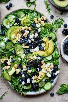 a salad with blueberries, cucumbers and avocado