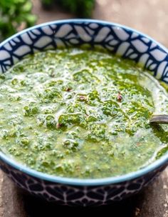 a blue and white bowl filled with broccoli soup on top of a wooden table