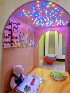 a child's bedroom decorated in pink and yellow with lights on the ceiling, stuffed animal sitting on bed