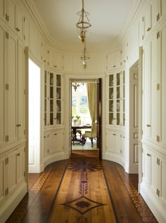 a hallway with white walls and wooden flooring next to an open door that leads to another room