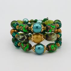 Pretty artisan made wire cuff bracelet easily fits a a 7-8 inch wrist. Made with beautiful selection of irredescent green art glass beads, faceted green glass beads, satin finished beads and round glass beads about to finish out the ends. Large beads of gold tone filigree bead caps. The color combination is wonderful with bright green foil glass and varying shades of green and gold satin finished beads. Bracelet is 1 1/4 inch wide and in very good vintage condition. Green Bohemian Stretch Bracelet With 8mm Beads, Bohemian Green Stretch Bracelet With 8mm Beads, Green Wrap Bracelet With Colorful Beads, Bohemian Green Beaded Crystal Bracelet, Green Beaded Bracelets With Spacer Beads As Gift, Green Stretch Bracelet With Colorful Beads For Party, Green Beaded Bracelets With Large Beads As Gift, Green Bohemian Stretch Bracelet With Faceted Beads, Green Wrap Bracelet With Round Beads For Gift