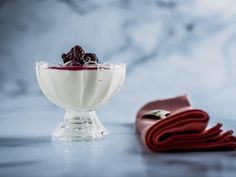 a glass bowl filled with yogurt and berries on top of a red napkin