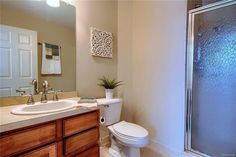 a white toilet sitting next to a bathroom sink under a shower stall with a glass door