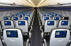 the inside of an airplane with rows of empty seats and blue screens on the windows