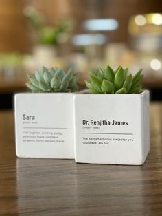 two small planters sitting on top of a wooden table