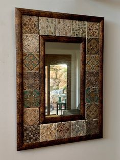 a mirror that is sitting on the wall next to a table with a vase in it